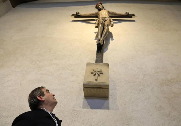 El hermano mayor de la hermandad mira a la imagen del Cristo en la cruz..