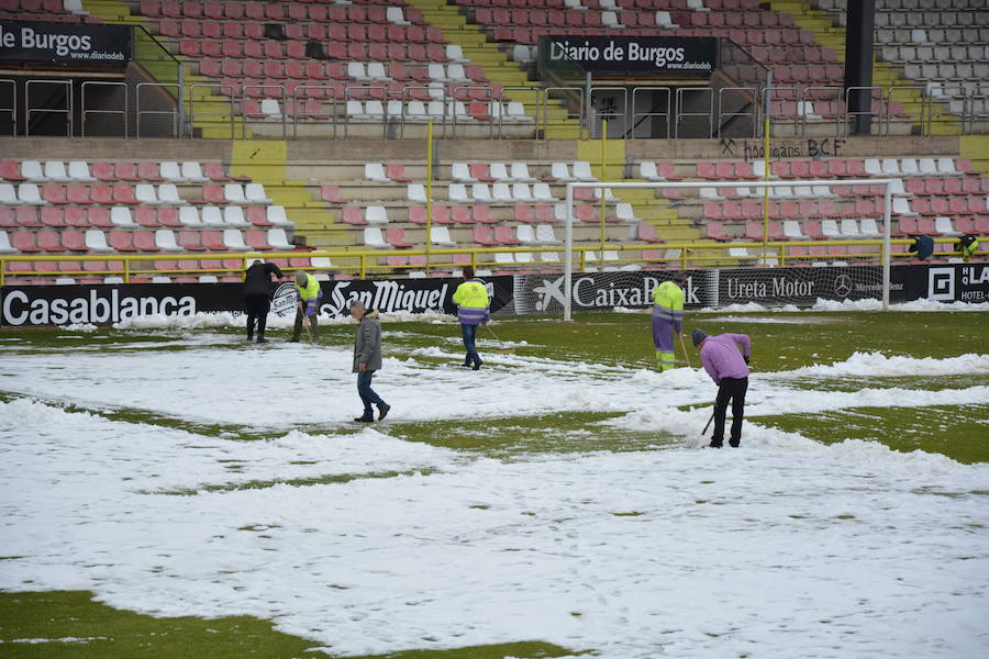 Operarios del servicio de mantenimiento del campo y voluntarios se afanan en retirar la nieve y el hielo del terreno de juego de El Plantío antes del Burgos CF - Barakaldo.