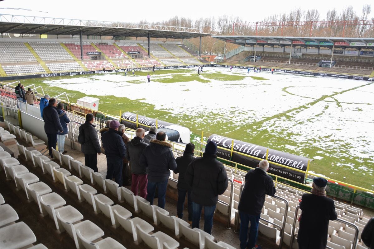 Operarios del servicio de mantenimiento del campo y voluntarios se afanan en retirar la nieve y el hielo del terreno de juego de El Plantío antes del Burgos CF - Barakaldo.