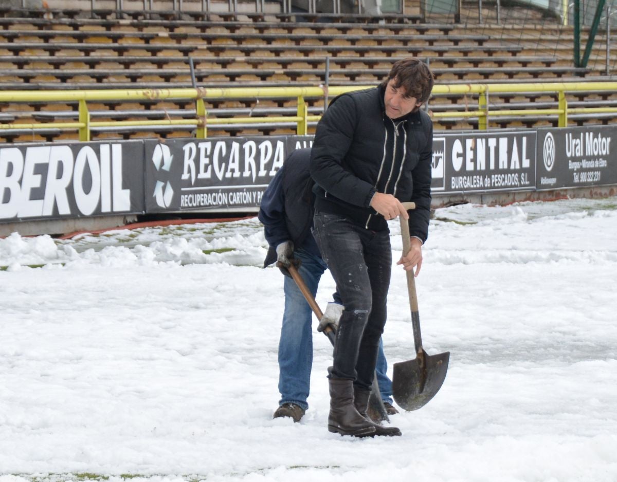 Operarios del servicio de mantenimiento del campo y voluntarios se afanan en retirar la nieve y el hielo del terreno de juego de El Plantío antes del Burgos CF - Barakaldo.