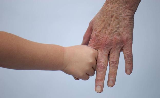 La mano de un niño agarrada a la de una anciana.