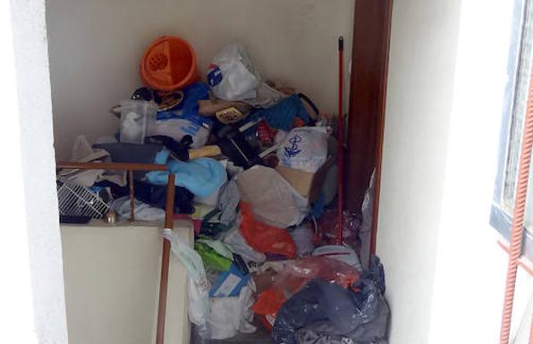 Basura acumulada en el rellano del piso de la mujer y la intervención (derecha) para sacarla del bloque de la calle Portillo de Balboa