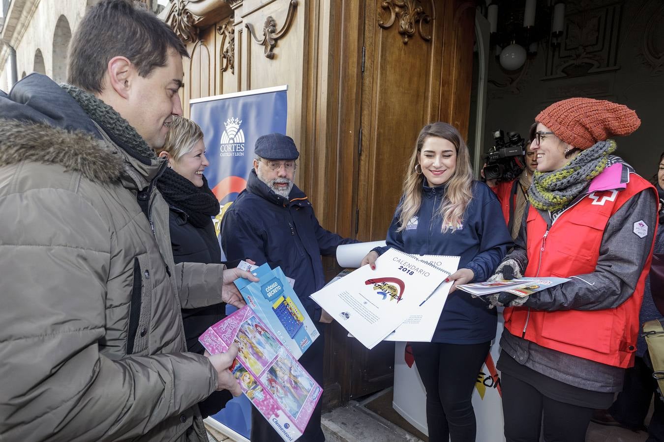 Los procuradores del PP Ángel Ibáñez e Irene Cortés entregan calendarios del aniversario del Estatuto CyL a cambio de juguetes.