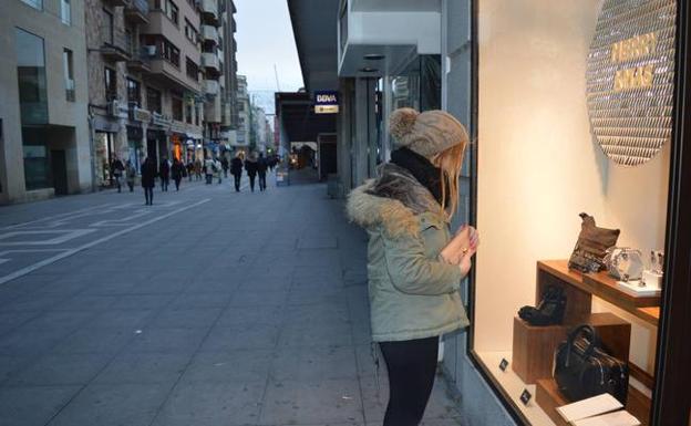 Una joven mira el escaparate de un comercio en la calle Santa Clara.