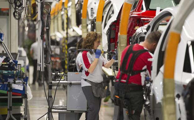 Varios trabajadores, en una cadena de montaje.