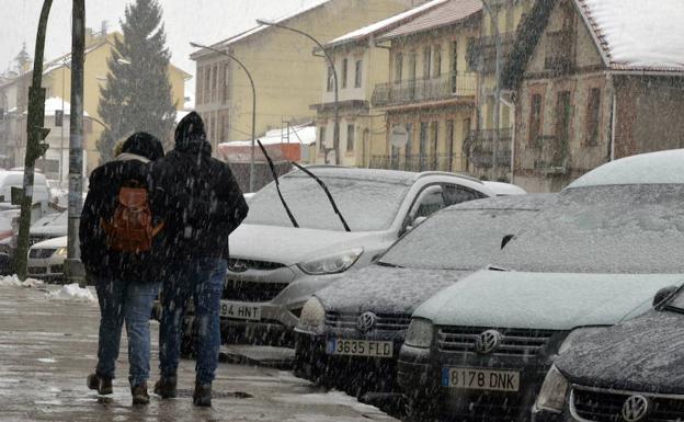 Unos jóvenes caminan por San Rafael durante la última nevada caída en esta zona de la provincia segoviana. 