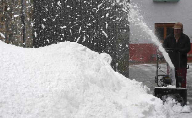 Un hombre quita nieve de las calles de Puebla de Lillo (León) durante el temporal que afecta al norte de la provincia.