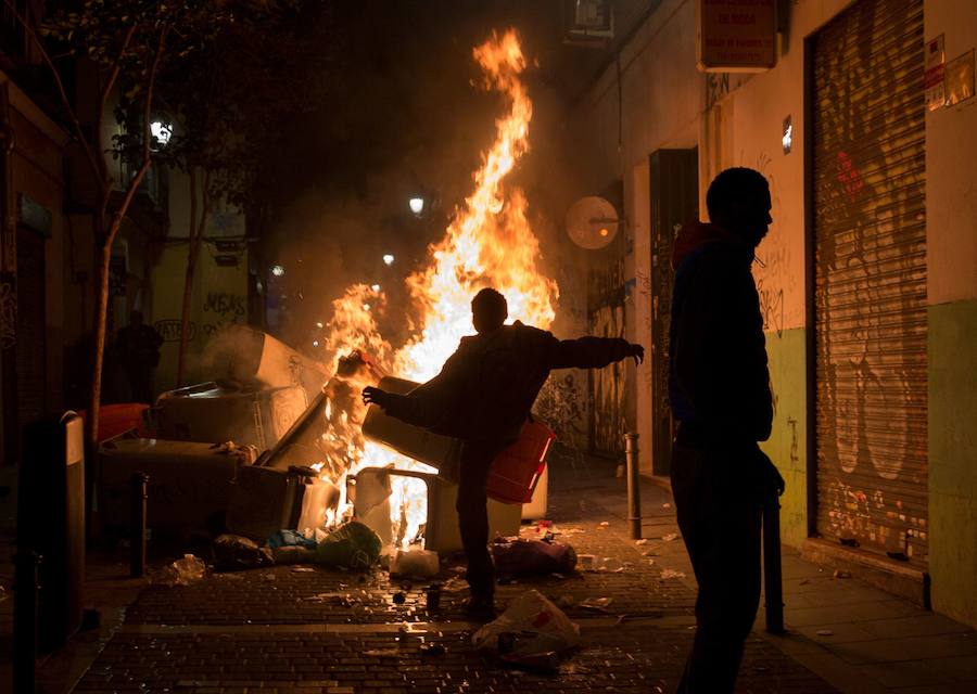 Un grupo de más de medio centenar de personas han quemado contenedores y causado desperfectos en el mobiliario urbano en el madrileño barrio de Lavapiés tras la muerte este jueves de un mantero de 35 años y origen subsahariano a causa de una parada cardiorrespiratoria.