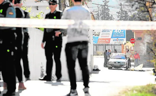 Los investigadores de la Guardia Civil inspeccionan el automóvil en el que fue acribillado el hombre, tras un cordón policial.