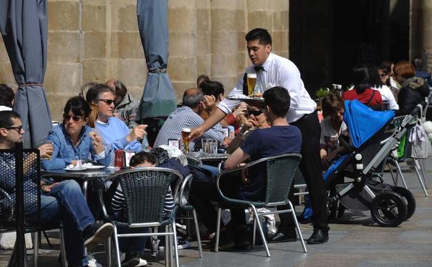 Un camarero atiende a los clientes en una terraza.