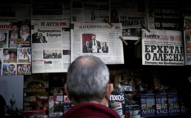 Un hombre mira varios períódicos en un quiosco de Grecia. 