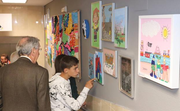 Un joven señala uno de los cuadros de la exposición de la Gerencia de Servicios Sociales.