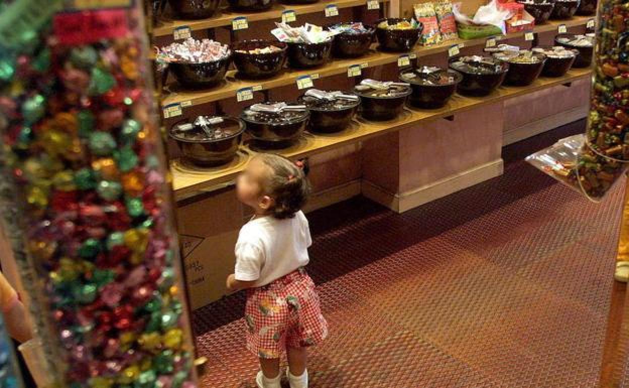 Una niña observa el mostrador de una tienda de golosinas.