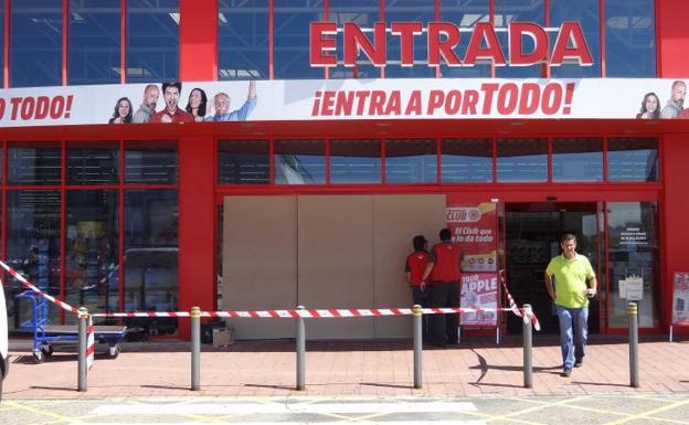 Empleados de Media Markt en Valladolid tapan con tablones de madera la puerta reventada por los ladrones.