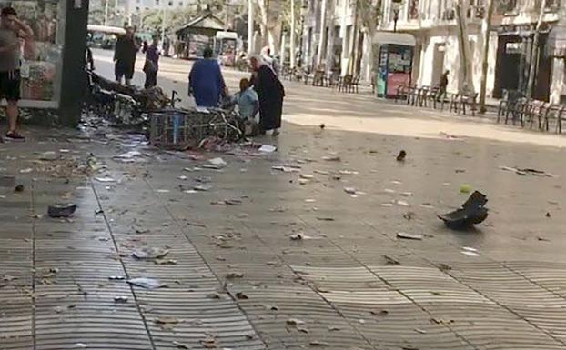 Varias personas atienden a un herido en el atentado terrorista de Las Ramblas. 