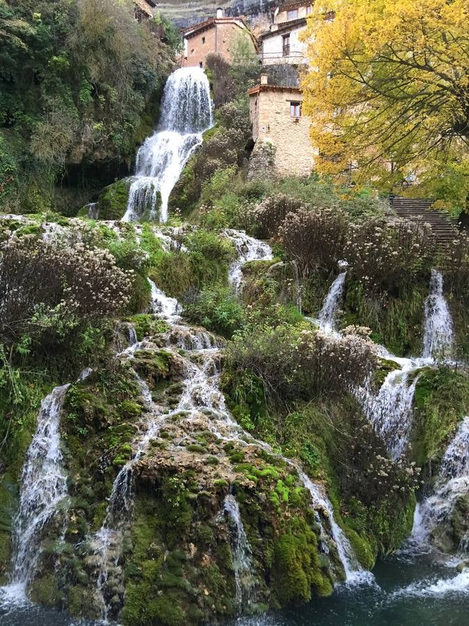 Cascada en Orbaneja del Castillo (Burgos). Las aguas del arroyo que brota de la cercana Cueva del Agua reflejan en su cristalina superficie -antes de precipitarse en una inolvidable cascada- las numerosas casas montañesas que se abren a las viejas y escalonadas rúas de un caserío que aprovecha, para su armoniosa ubicación, unas escasas y estrechas terrazas tobáceas. Orbaneja del Castillo y su entorno conforman uno de los paisajes más espectaculares de la geografía burgalesa.