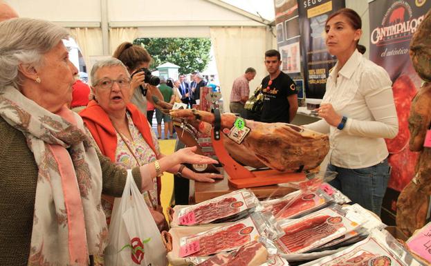 Una mujer atiende a varias clientas que están interesadas en comprar productos del cerdo.