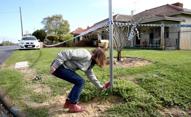 Una mujer deposita una flor frente a la casa de las víctimas. 