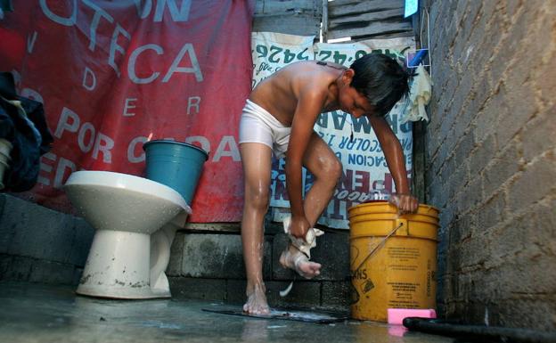 Un niño mexicano se lava con agua de un cubo antes de ir al colegio. 