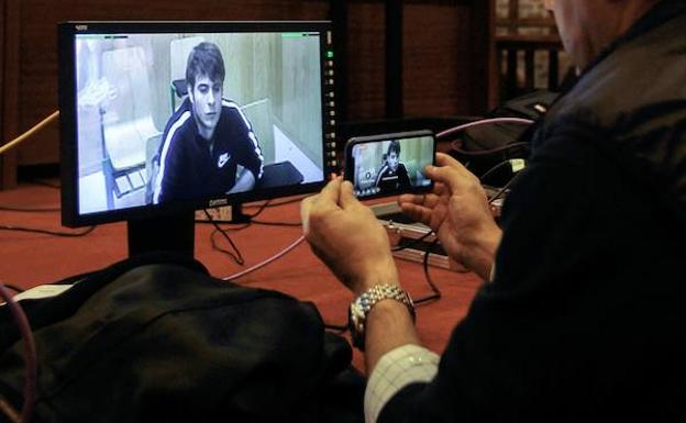 Un periodista toma imágenes de una televisión en la que se muestra al acusado Patrick Nogueira. 