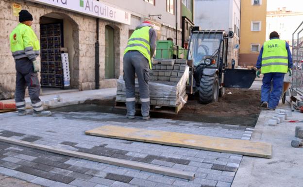 Varios trabajadores colocan los nuevos adoquines.