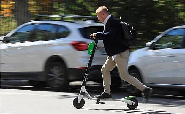 Un hombre monta sobre un patinete de la empresa Lime en Madrid.