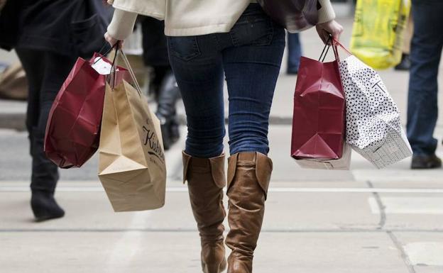 Una mujer camina con bolsas. 