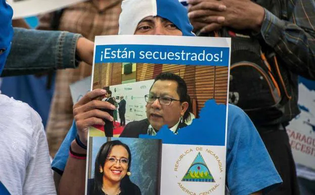 Un hombre sostiene las fotos de los periodistas Lucía Pineda y Miguel Mora.