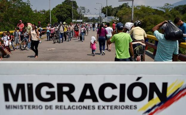 Varias personas cruzan la frontera entre Venezuela y Colombia. 