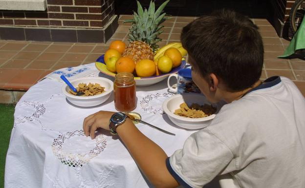 Un niño desayuna comida sana a base de frutas y cereales. :: 