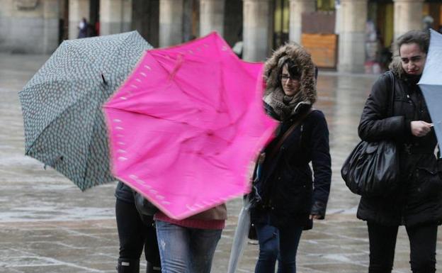 Un grupo de jóvenes se protegen del viento y la lluvia en Salamanca.