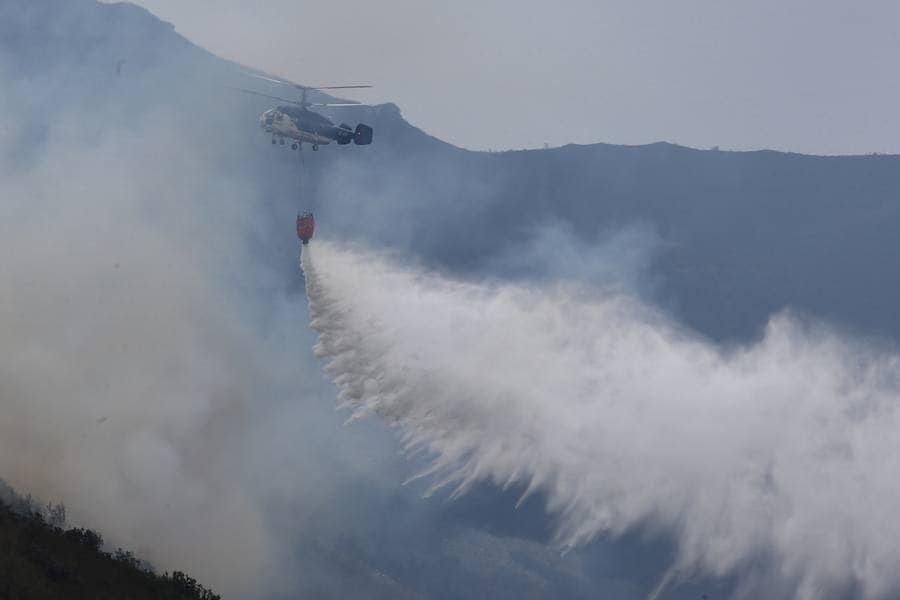 Un helicóptero vierte agua en el incendio del consejo asturiano de Salas.