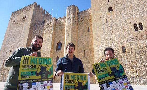 Miembros de la Asociación Cultural Medinarachas muestran el cartel de la III edición de Medina Sambea. 