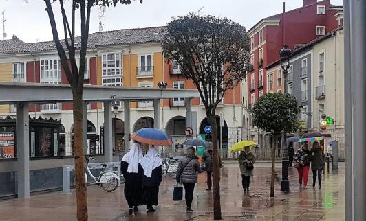 En primer plano, dos religiosas se protegen de las inclemencias meteorológicas.