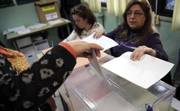 Una mujer introduce su voto en una urna.