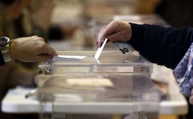 Una mujer introduce su voto en una urna. 