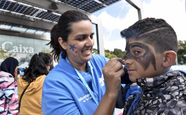 Una voluntaria de 'la Caixa' pinta la cara a un niño. 