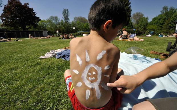 Una madre pone crema solar a su hijo. 