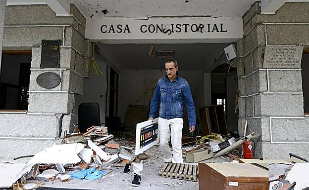Un hombre saca un cuadro del Ayuntamiento de la localidad orensana de Beade, tras la explosión de un artefacto colocado en la puerta del consistorio, dentro de una olla a presión, en octubre de 2013. 