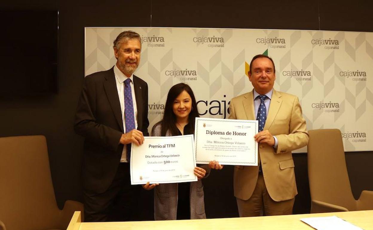 La autora del mejor Trabajo Fin de Máster (TFM), Mónica Ortega, recibe los diplomas acreditativos del premio de la mano del rector de la Universidad de Burgos, Manuel Pérez Mateos (izquierda) y el director general de Cajaviva Caja Rural, Ramón Sobremonte.