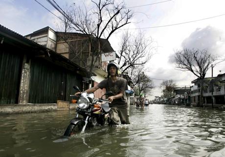 Imagen - Un indonesio empuja su moto por una calle inundada de la zona norte de Yakarta el 10 de diciembre de 2007. /EFE