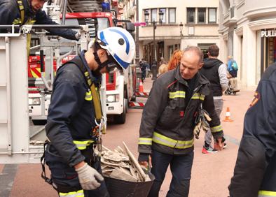 Imagen secundaria 1 - Viandantes observando la medianera (centro), los bomberos bajan un cubo con cascotes (izquierda) y aspecto de la pared (derecha).