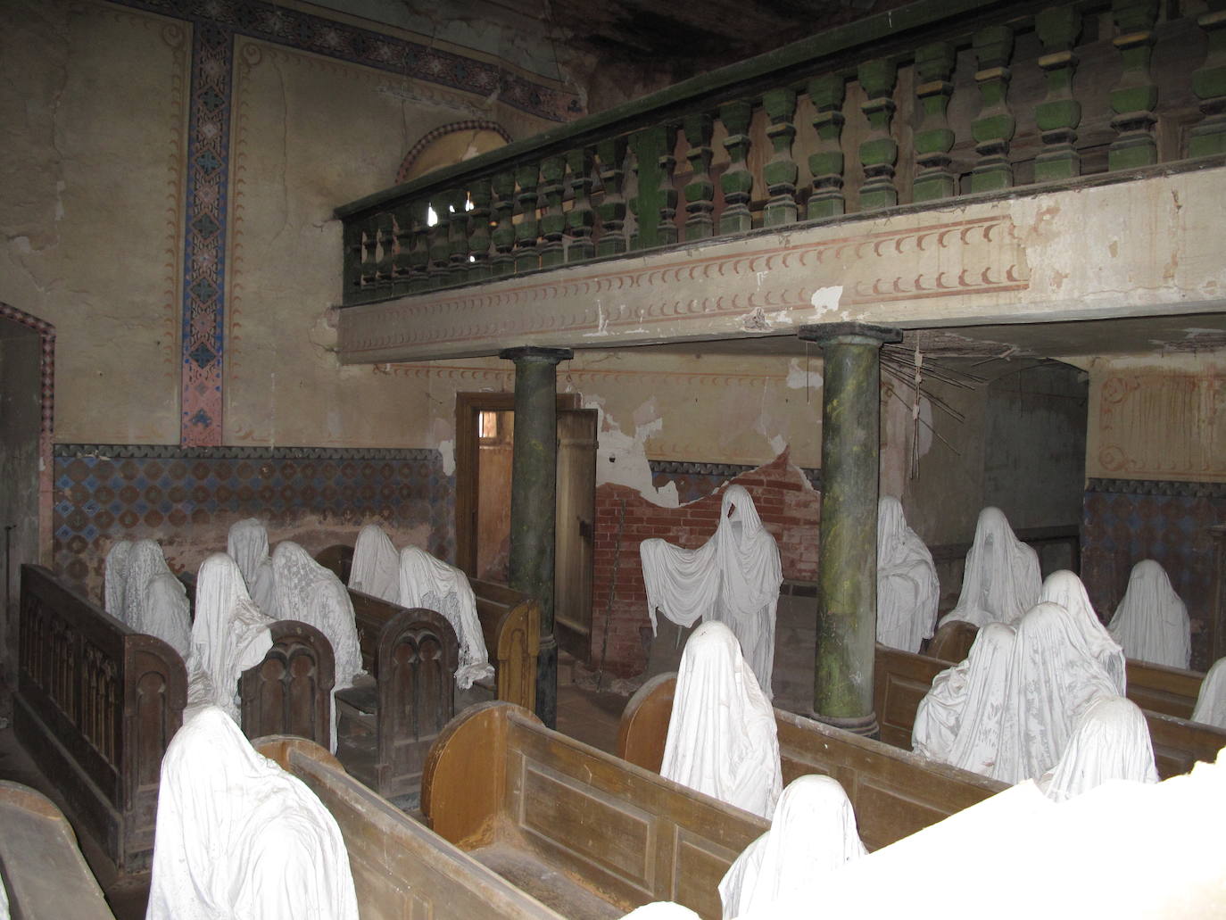 Iglesia de San Jorge (Lukova, República Checa) | Fue construida en el siglo XIV, en torno al año 1352. En 1968, durante un funeral parte del techo se vino abajo y los residentes del lugar lo vieron como un mal presagio. Los rumores comenzaron a circular y pronto la iglesia alcanzó el estatus de maldita. Desde entonces, había permanecido cerrada hasta que en el 2014 Jakuv Hadrava convirtió su espacio en parte de su proyecto de tesis. El artista ideó una obra constituida por varias figuras fantasmales realizadas a tamaño natural que colocó aleatoriamente en la sala de oración como si fueran asistentes de una misa perpetua. 