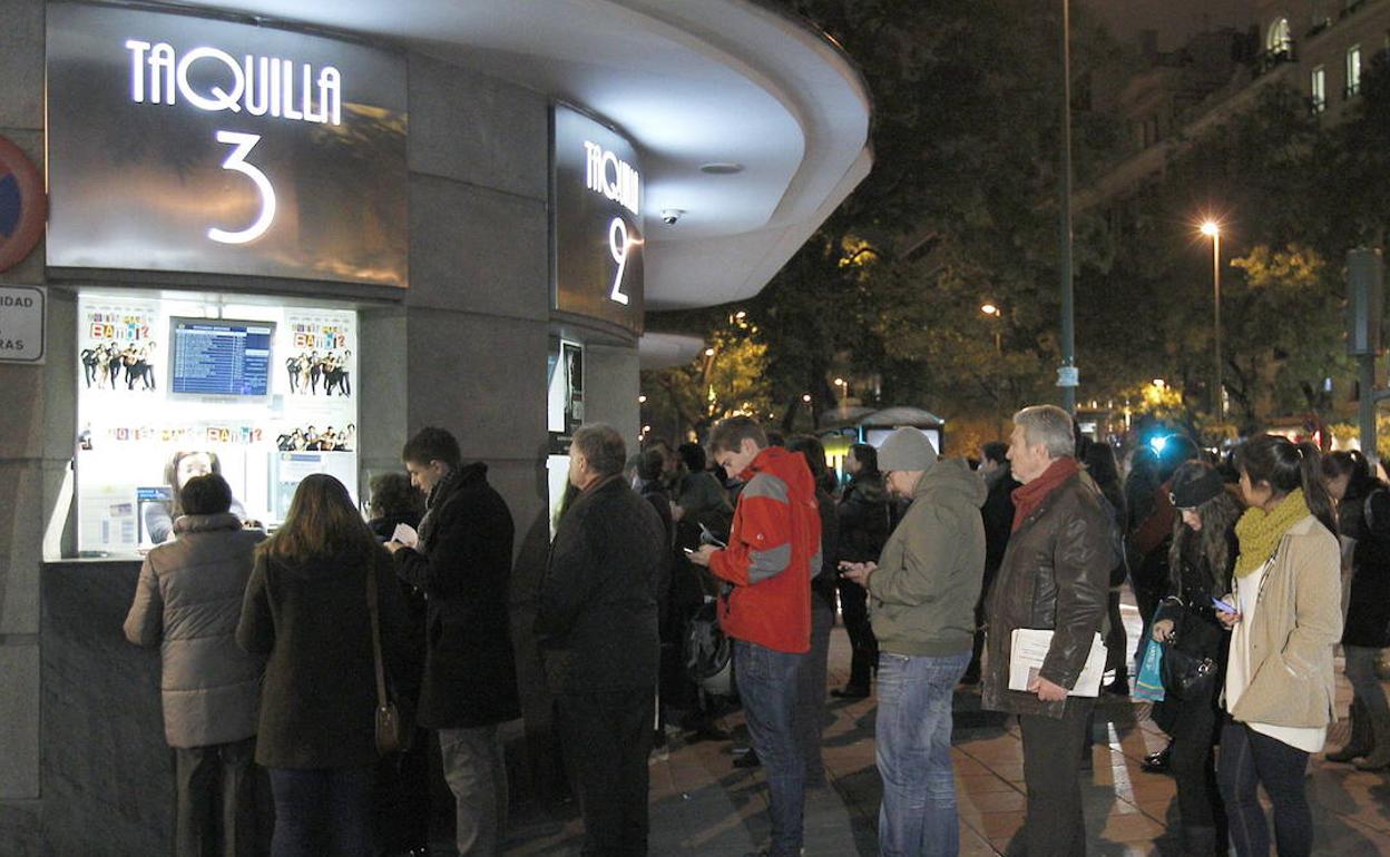 Gente hace cola en las taquillas de una sala de cine. 