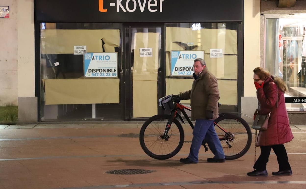 Un señor lleva su bicicleta de la mano en el centro de la ciudad.