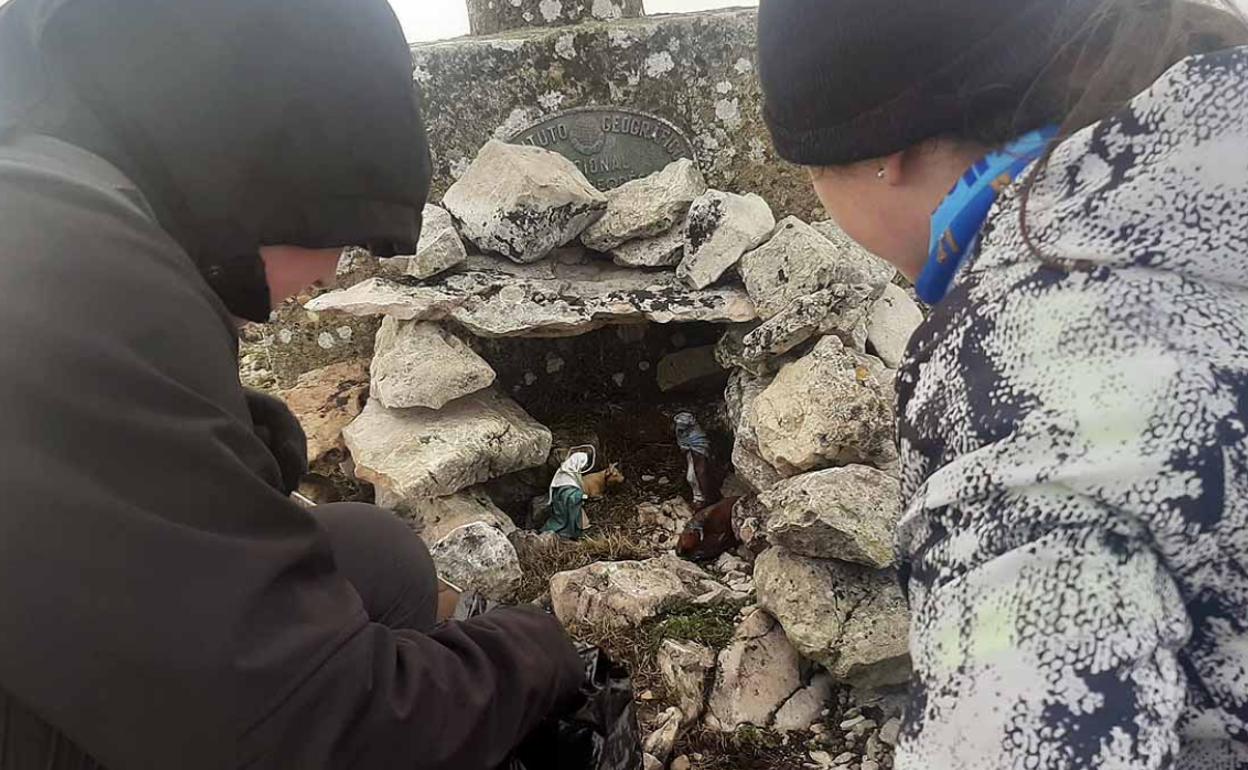 Dos montañeros observan el belén instalado en la cumbre de la Sierra de La Tesla. 