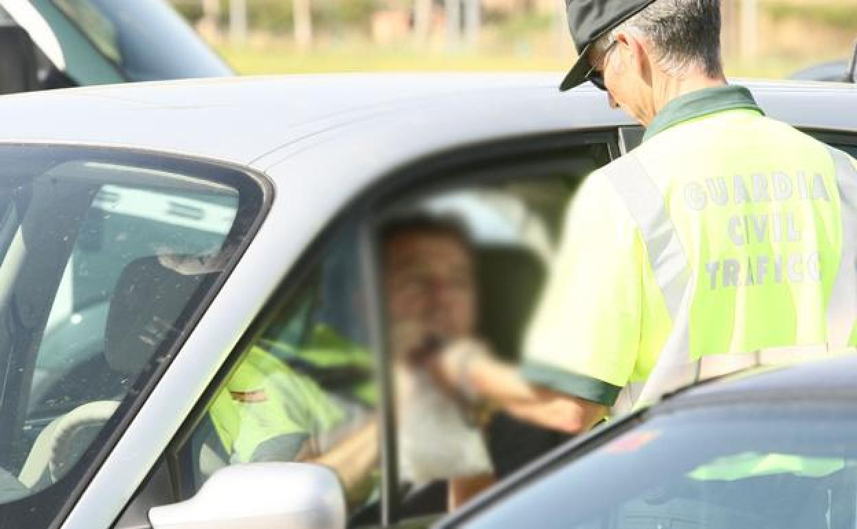 Un guardia civil realiza una prueba de alcoholemia a un conductor. 