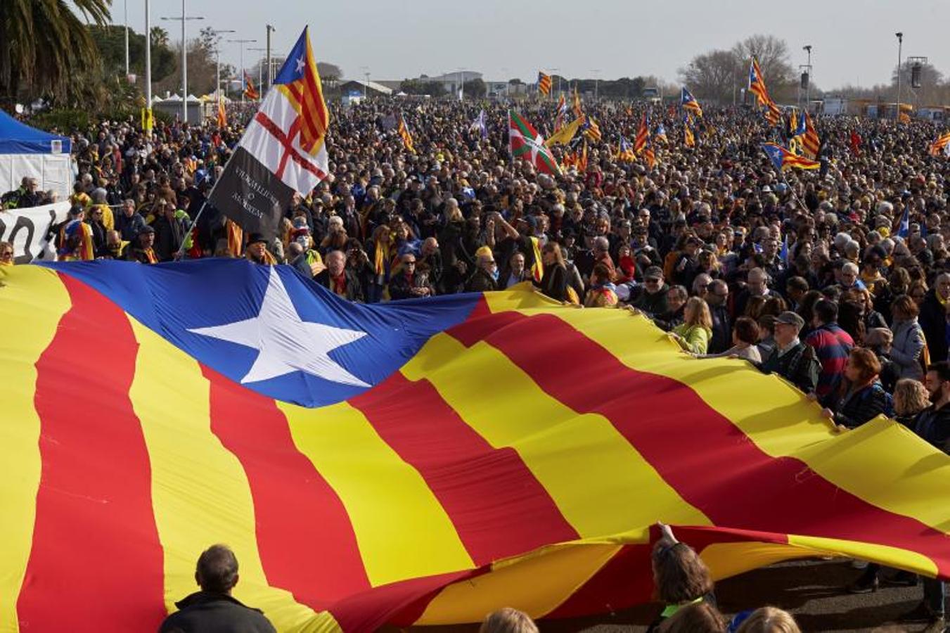 Miles de personas que asisten este sábado al acto protagonizado por Carles Puigdemont despliegan una estelada en un parque de la localidad francesa de Perpiñán.