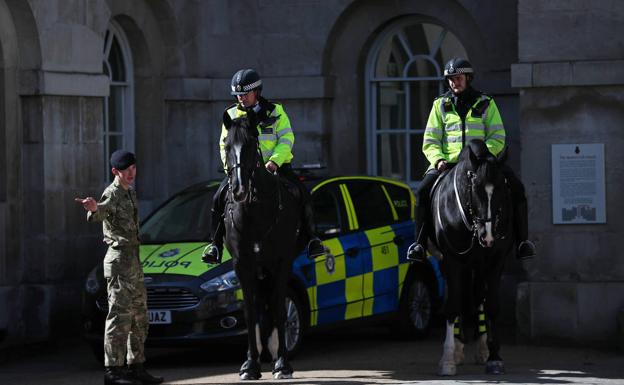 Dos oficiales de polícia hablan con un miembro del Ejército británico en Londres