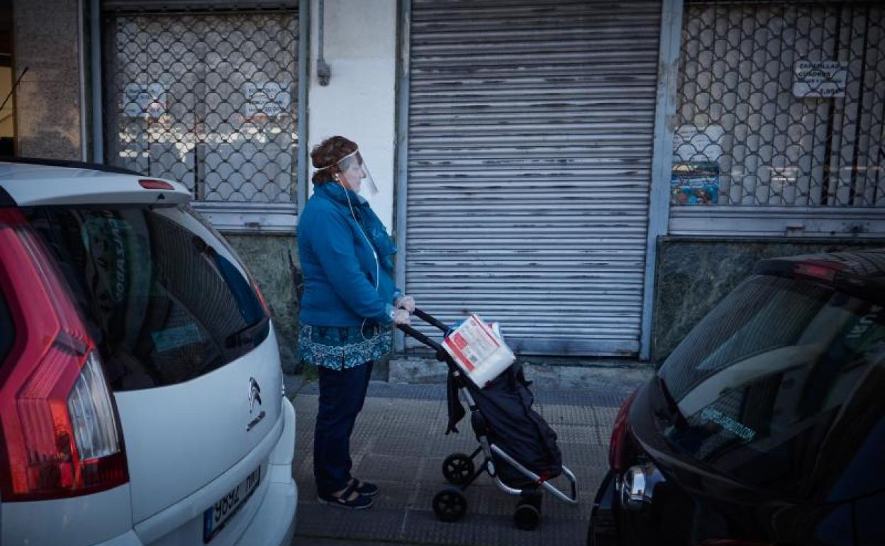 Una mujer protegida con una pantalla de plástico regresa de la compra en Pamplona. 